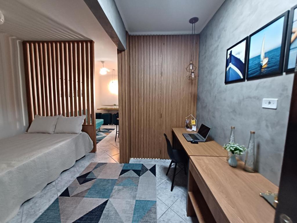 une chambre avec un lit et un bureau avec un ordinateur portable dans l'établissement Apartamento Aconchegante, à Praia Grande