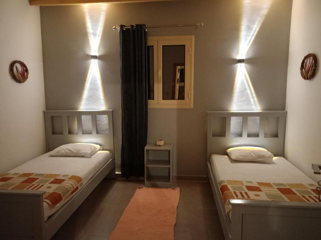 - 2 lits dans une chambre avec des lumières sur le mur dans l'établissement Studio with a spacious garden in Al-Assla, à Dahab