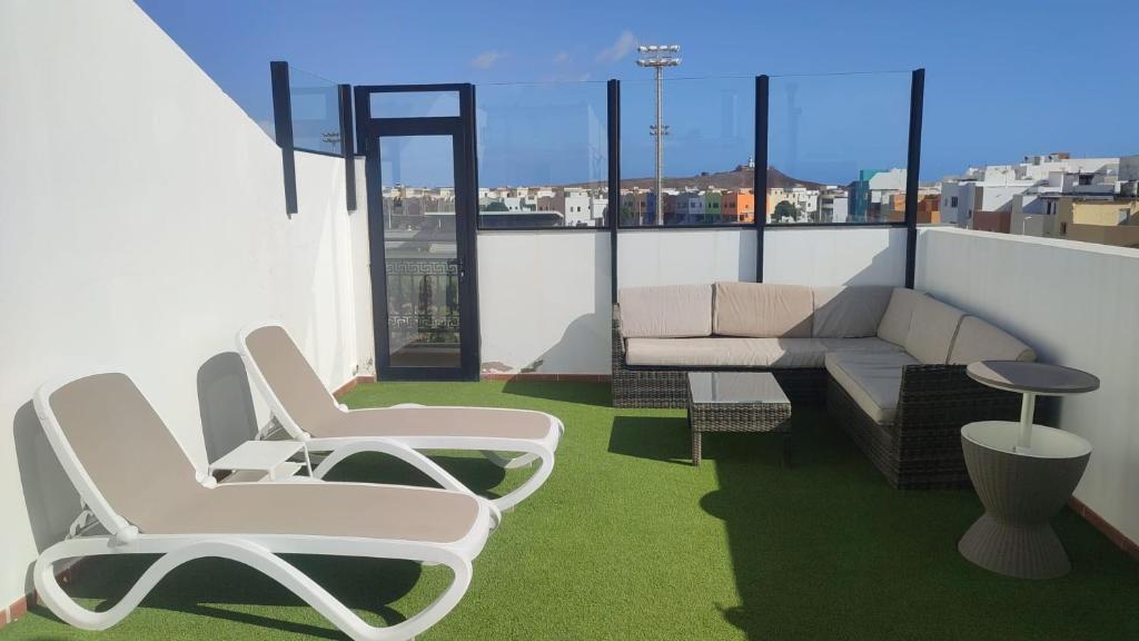 un balcone con 2 sedie e un divano sul tetto di Apartamentos Risco Verde a Arinaga