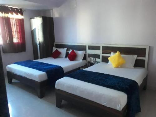 a bedroom with two beds with blue and yellow pillows at C P Hotel in Mahabaleshwar