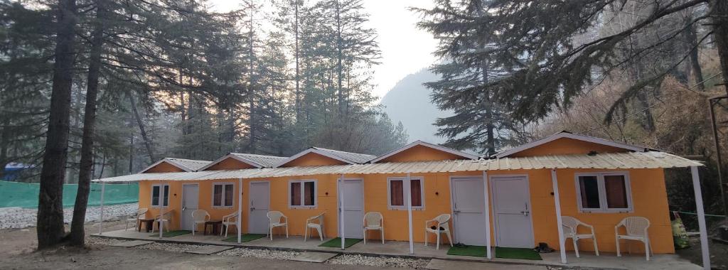 an orange building with chairs in front of it at Pandora Riverside Cafe & Stay in Kasol