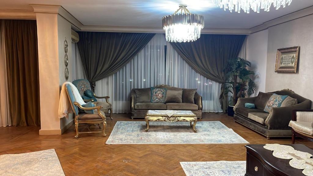 een woonkamer met banken en stoelen en een kroonluchter bij Luxury Apartment Nasr City in Caïro