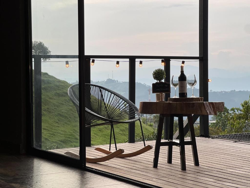 einen Tisch mit Weingläsern und einen Stuhl auf dem Balkon in der Unterkunft Glamping Ocaso in Llanitos