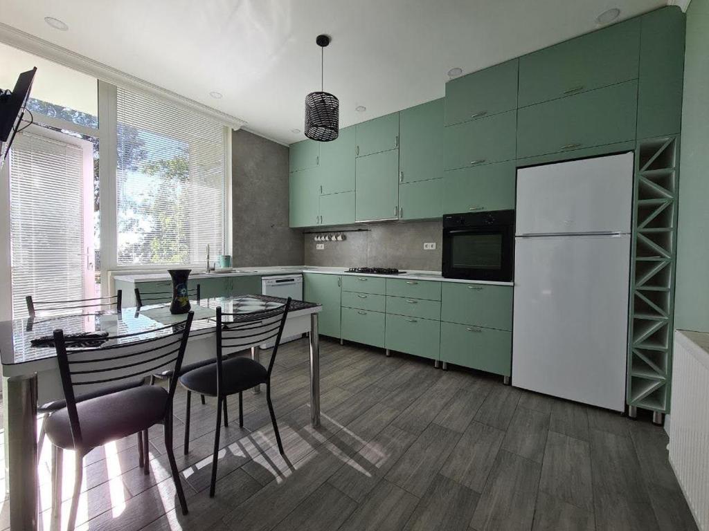 a kitchen with green cabinets and a table with chairs at Villa TG in Batumi