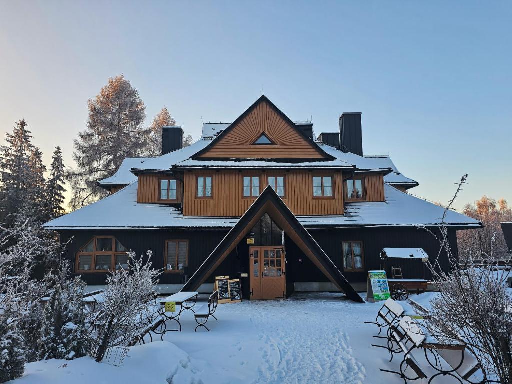 duży drewniany dom z śniegiem na ziemi w obiekcie SCHRONISKO GOŚCINIEC RÓWNICA w Ustroniu