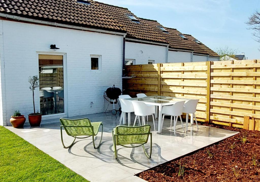 eine Terrasse mit Tisch und Stühlen und einem Zaun in der Unterkunft Salty - Vakantiehuisje op de grens van Bredene-De Haan in Bredene