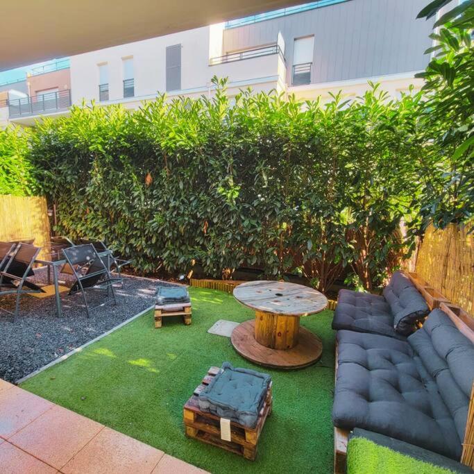 une arrière-cour avec une table, un canapé, une table et un sidx de table dans l'établissement T2 COSY&CALME proche PARIS/ORLY, à La Ville-du-Bois