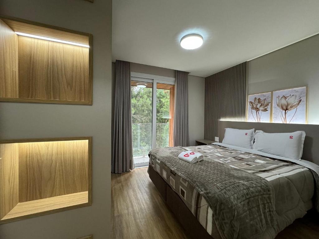um quarto com uma cama grande e uma janela em Alpes da Montanha 404 - Apê Novo em Gramado em Gramado