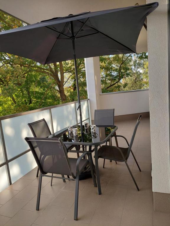 a table and chairs with an umbrella on a balcony at Apartament in Legionowo