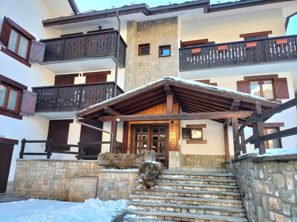 a building with stairs in front of it in the snow at Delizioso appartamento in centro a Champoluc in Champoluc