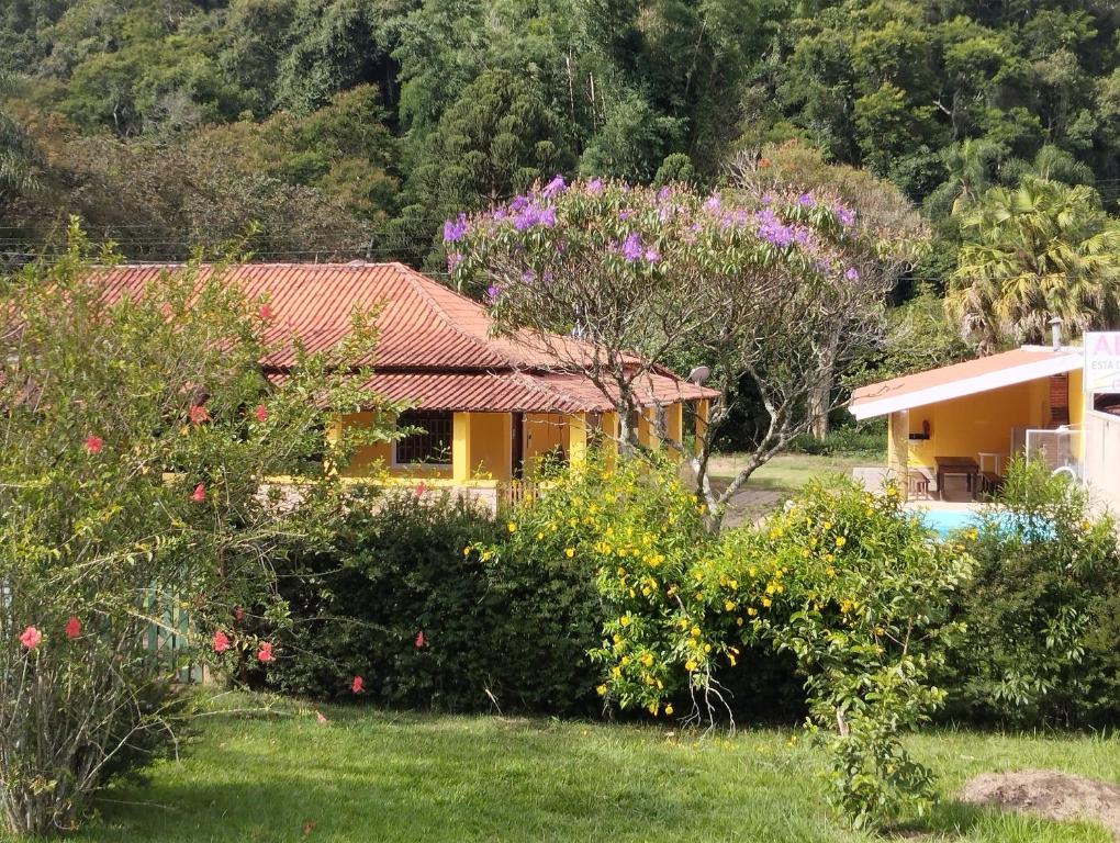 une maison avec une cour ornée de fleurs et d'arbres dans l'établissement Chácara Portal dos Anjos, à Cunha