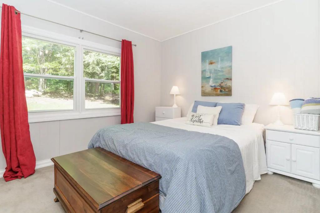 1 dormitorio con 1 cama y una ventana con cortinas rojas en The Lakehouse, en Carnarvon