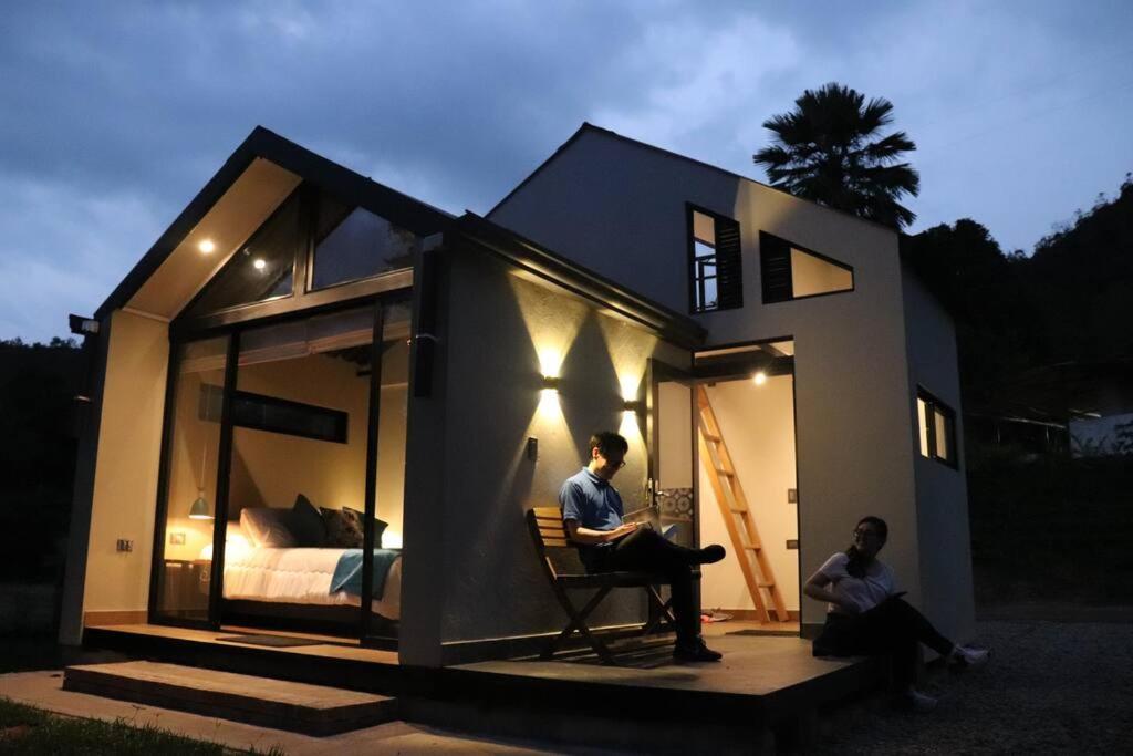 dwoje ludzi siedzących przed małym domem w obiekcie Luxury Glamping - Tiny House al natural w mieście La Vega