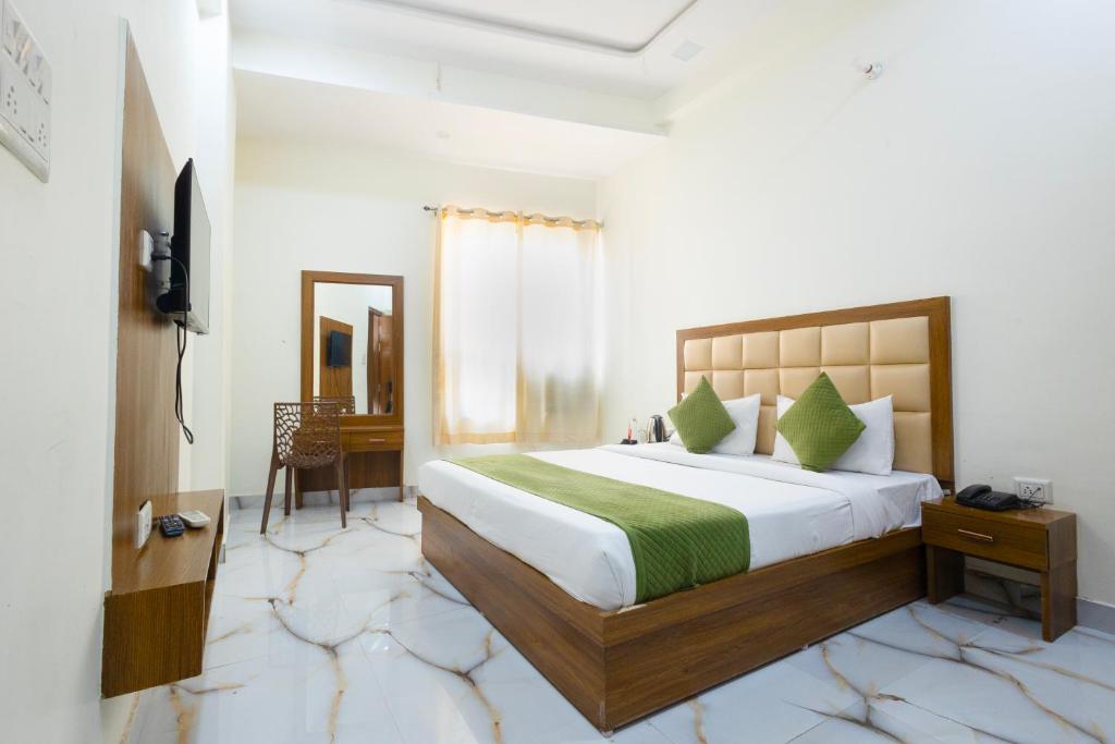 een slaapkamer met een groot bed en een televisie bij Hotel Lime Tree by Madhav in Mathura