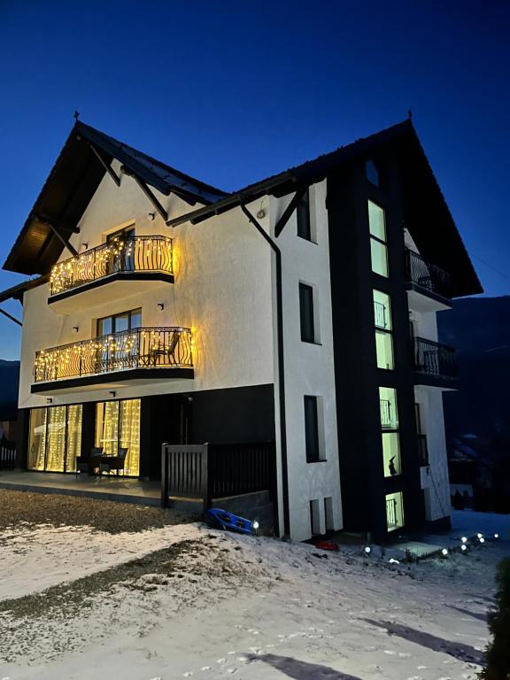 ein Schwarz-Weiß-Gebäude mit einem Balkon in der Unterkunft Transylvania House in Moieciu de Jos