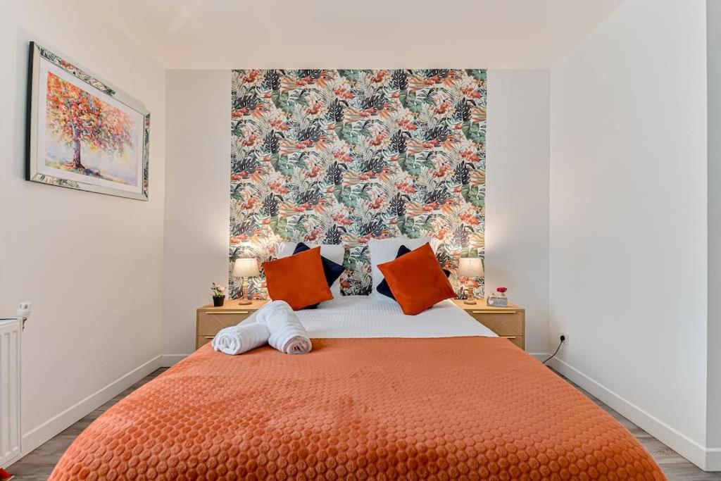 una camera da letto con letto arancione e cuscini arancioni di Charmant duplex à deux pas de Paris et du RER B a Gentilly