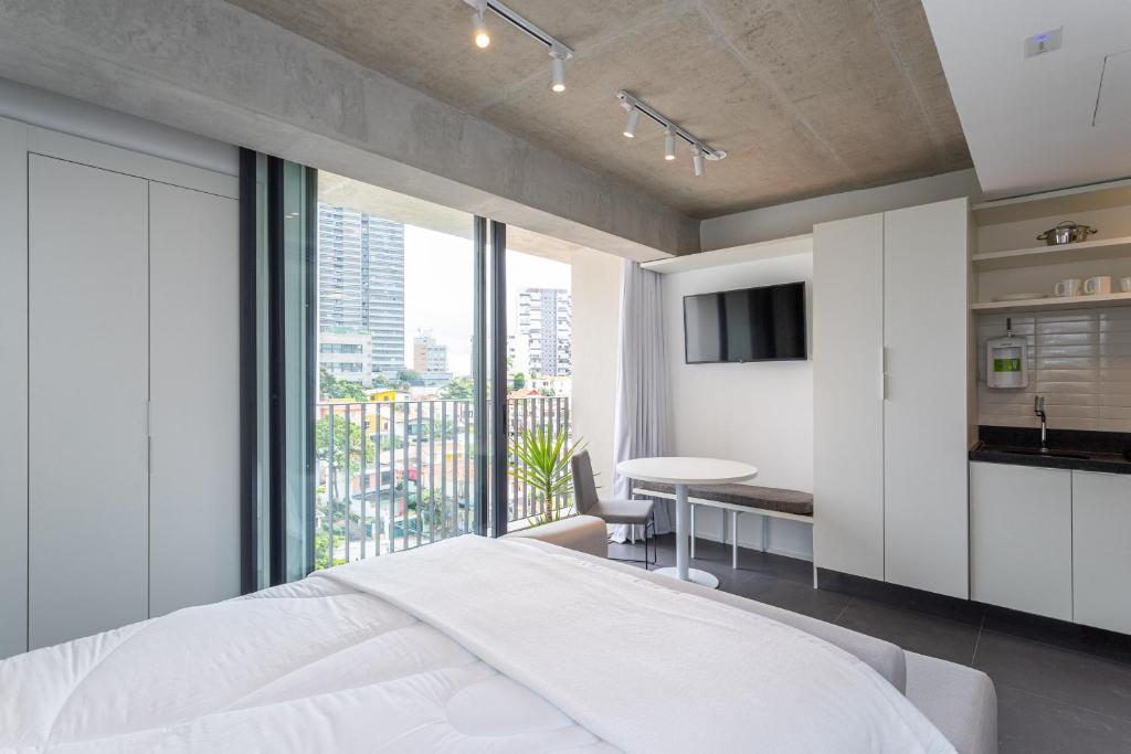 une chambre avec un lit, une table et une fenêtre dans l'établissement Charlie Onze22 Vila Madalena, à São Paulo