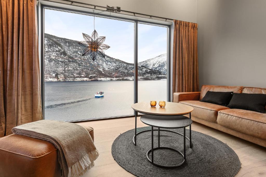 ein Wohnzimmer mit einem großen Fenster mit einem Sofa und einem Tisch in der Unterkunft Toppleilighet på bryggen i Sogndal med fantastisk utsikt in Sogndal