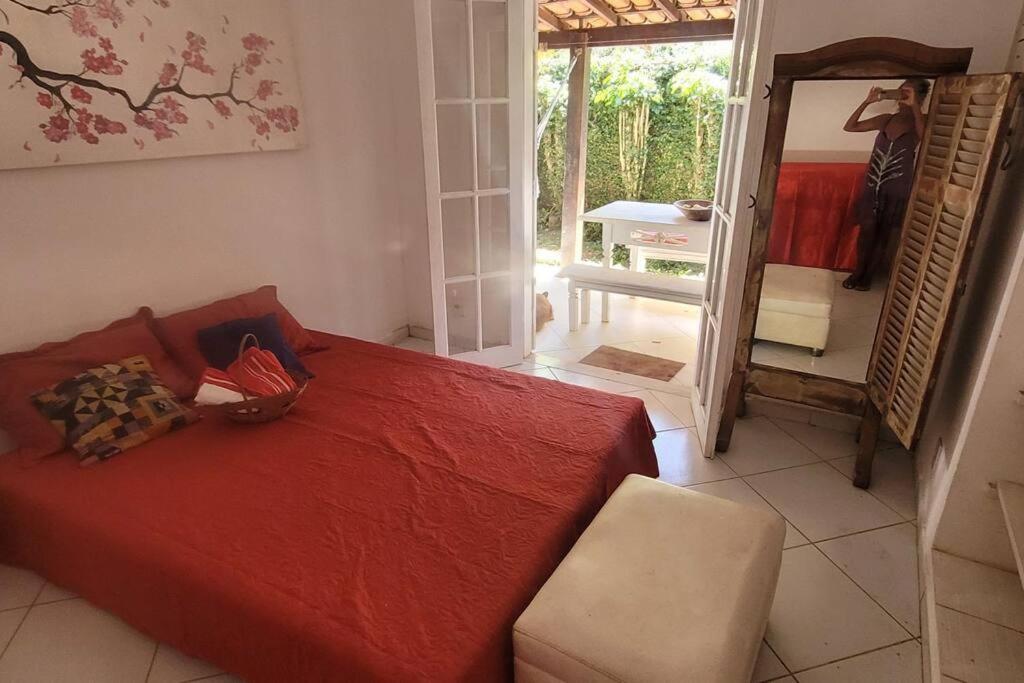 a bedroom with a red bed and a mirror at Canto sossego casa independente a passos do mar in Búzios
