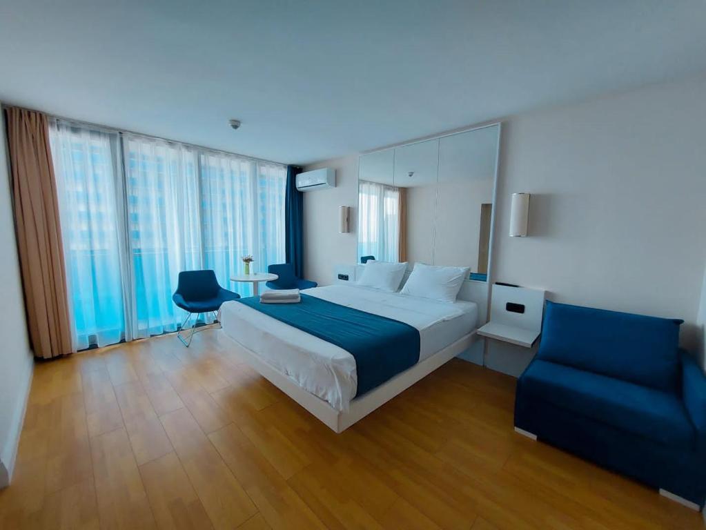 a bedroom with a large bed and a blue chair at Orbi city - Premium Class Rooms in Batumi
