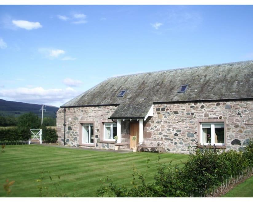 a stone house with a grassy yard in front of it at Fairness Cottage, Near Comrie in Comrie