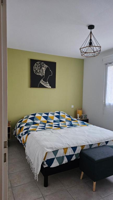1 dormitorio con 1 cama grande y edredón colorido en Bel appartement F3 tout confort, en Saint-Vincent-de-Paul