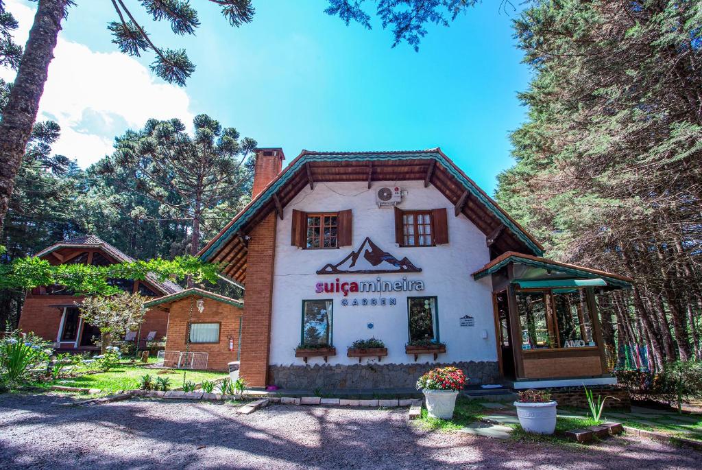 uma casa no meio de uma floresta com árvores em Pousada Suiça Mineira Garden em Monte Verde