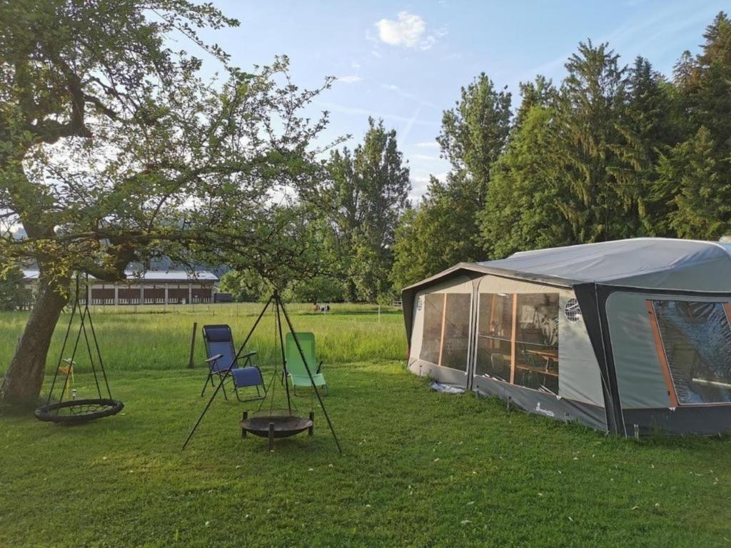 a tent and two chairs in a field at Familienwohnwagen im Emmental 