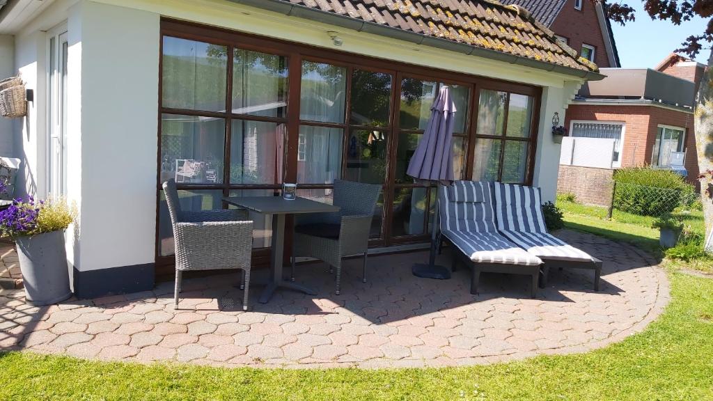 een patio met een tafel, 2 stoelen en een parasol bij Ferienwohnung Deichblick in Tönning