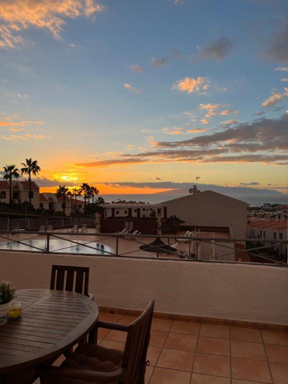 アデへにあるAdele apartment Costa Adejeの夕日を望むバルコニー(テーブル、椅子付)