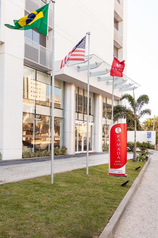 a building with three flags in front of it at Ramada Hotel & Suites Campos Pelinca in Campos dos Goytacazes