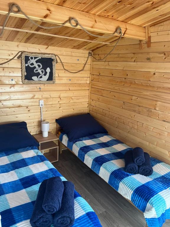 two beds in a room with wooden walls at Swojskie Chatki - Marynarska Chatka in Smołdziński Las