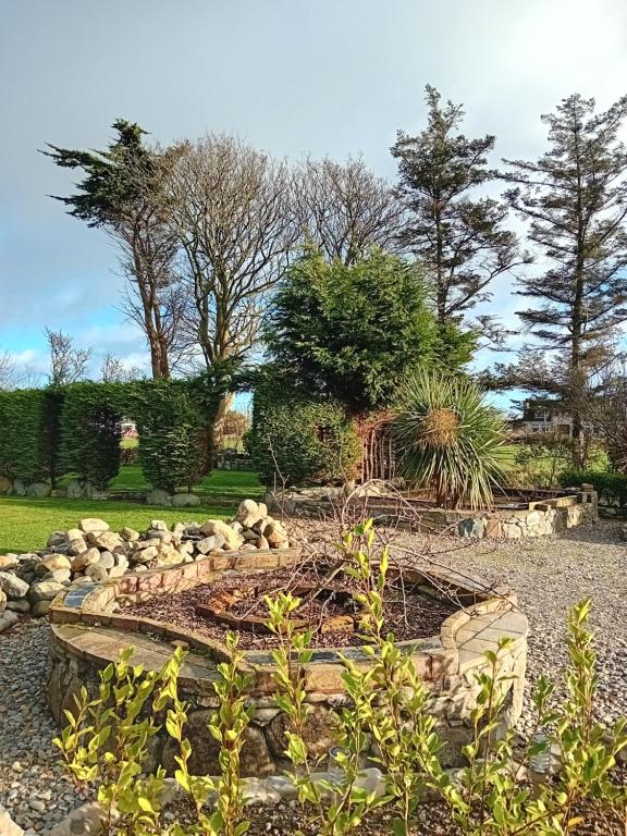 a garden with a stone retaining wall and trees at Carlingford Glamping Hut in Rathcor Lower