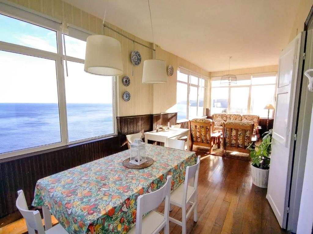 a dining room with a table and chairs and the ocean at Mirando al mar, itxas gane in Elanchove