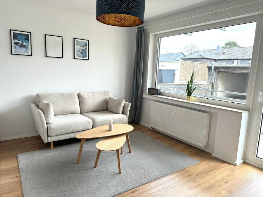a living room with a couch and a table and a window at Moderne 2 Zimmer Wohnung (52qm) am CentrO! in Oberhausen