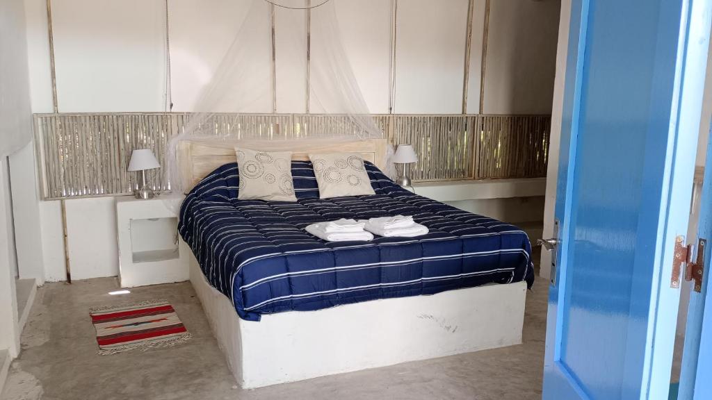 a bedroom with a blue and white bed with pillows at Habitación payesa en el bosque, La Barra in Barra de Maldonado