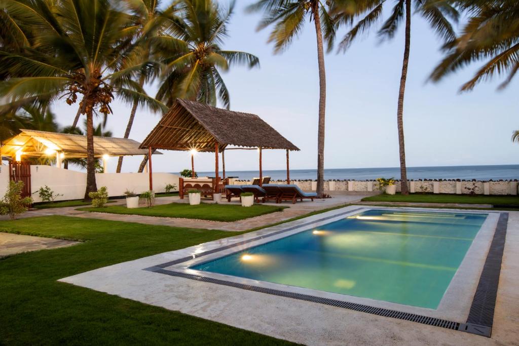 a swimming pool with a gazebo and the ocean at Oasys House - Beautiful Private Beach Front Home in Msambweni