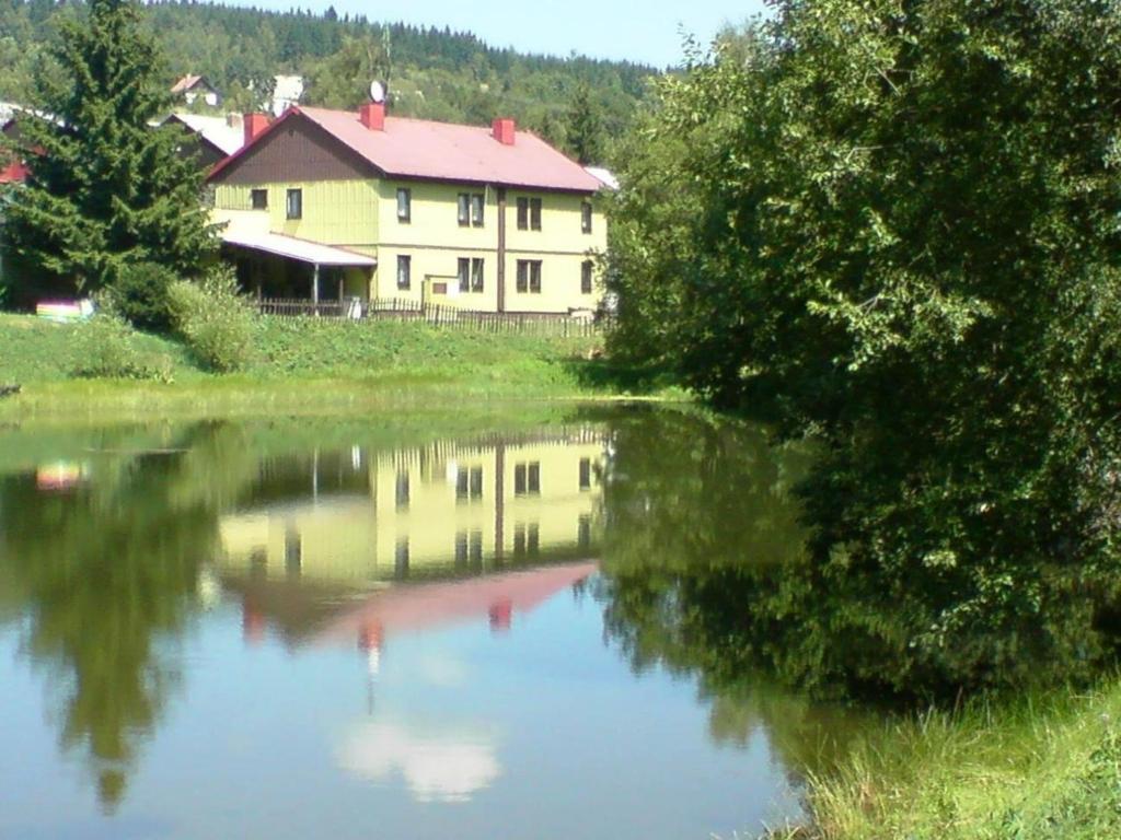 ein Haus neben einem See mit einem Gebäude in der Unterkunft Beide Ferienwohnungen befinden sich direkt am kleinen Bergsee mit Blick auf den Wald in Mariánská