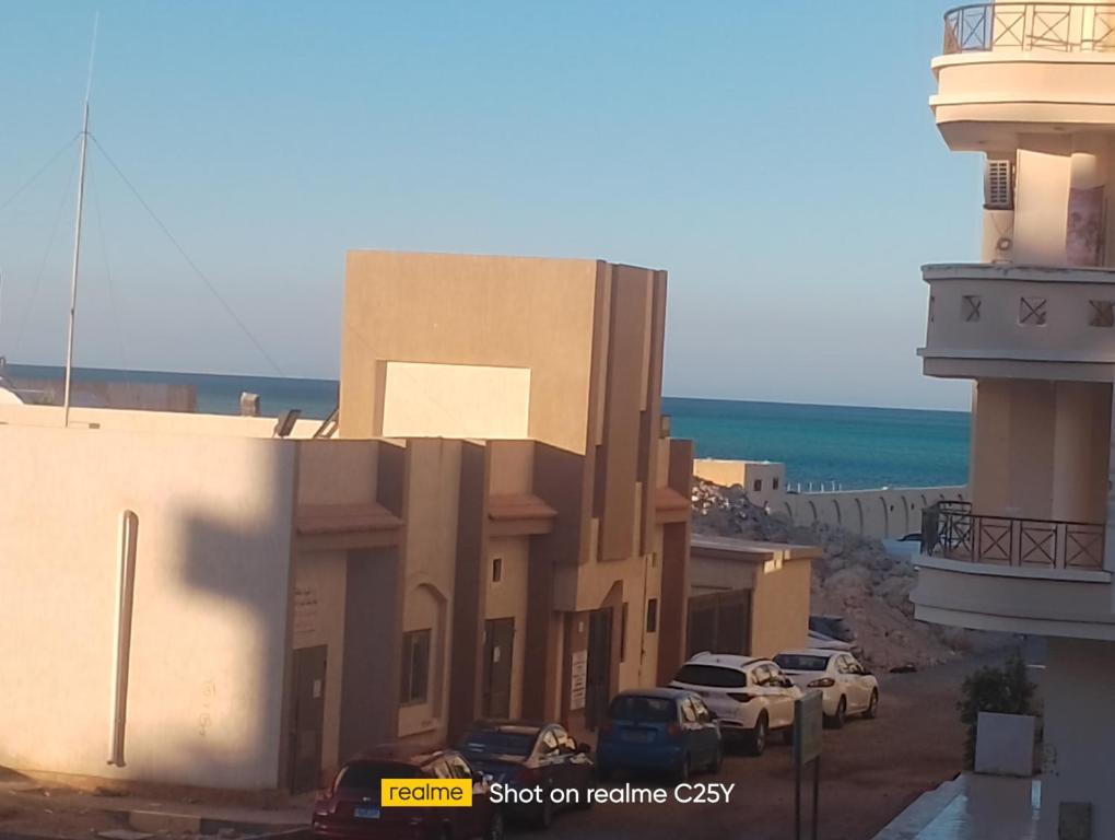 a building with cars parked in a parking lot next to the ocean at الفيروز in Hurghada