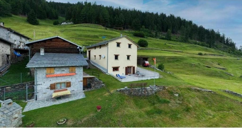 an aerial view of a house on a green hill at Monte Campell Dasura in Poschiavo