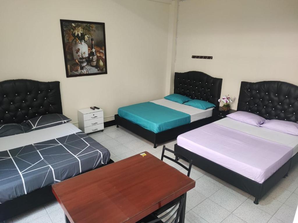 um quarto com três camas e uma mesa em La Gran Mansión en el corazón de Pereira em Pereira