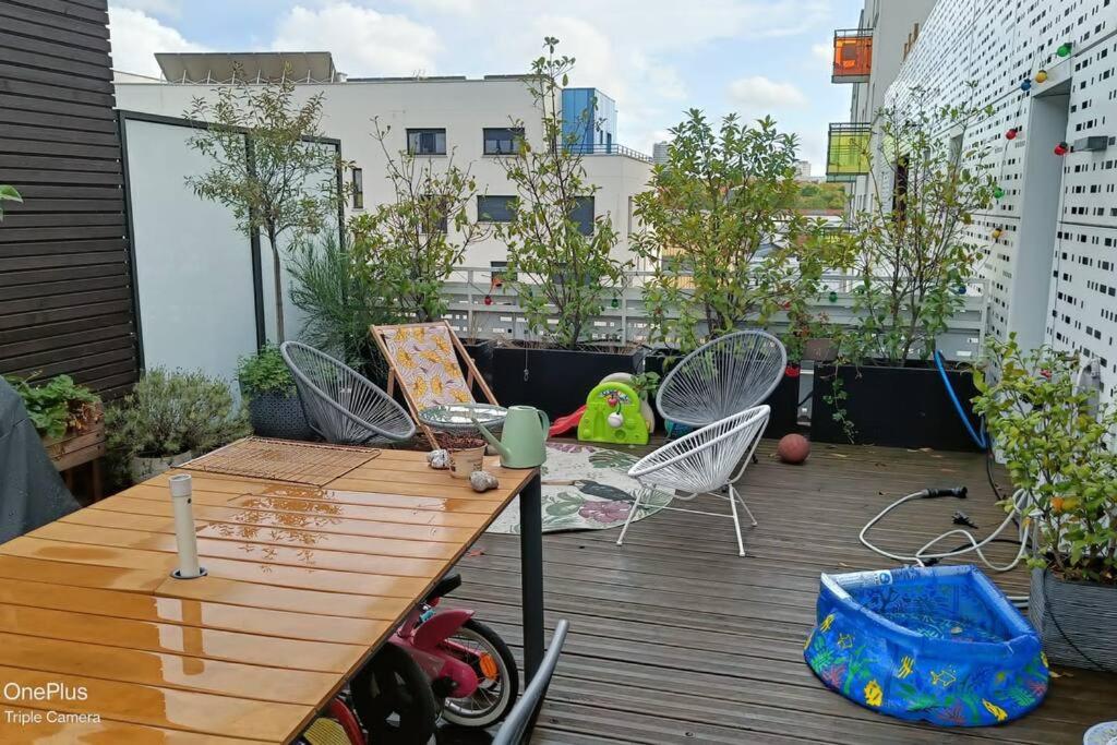 a patio with a wooden table and chairs on a balcony at Appartement avec terrasse in Saint-Denis