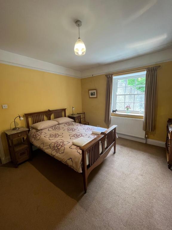 a bedroom with a large bed and a window at Torside Holiday Cottage in Castleton
