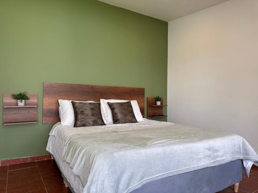 1 dormitorio con 1 cama grande y paredes verdes en Casa Niza, en Bogotá