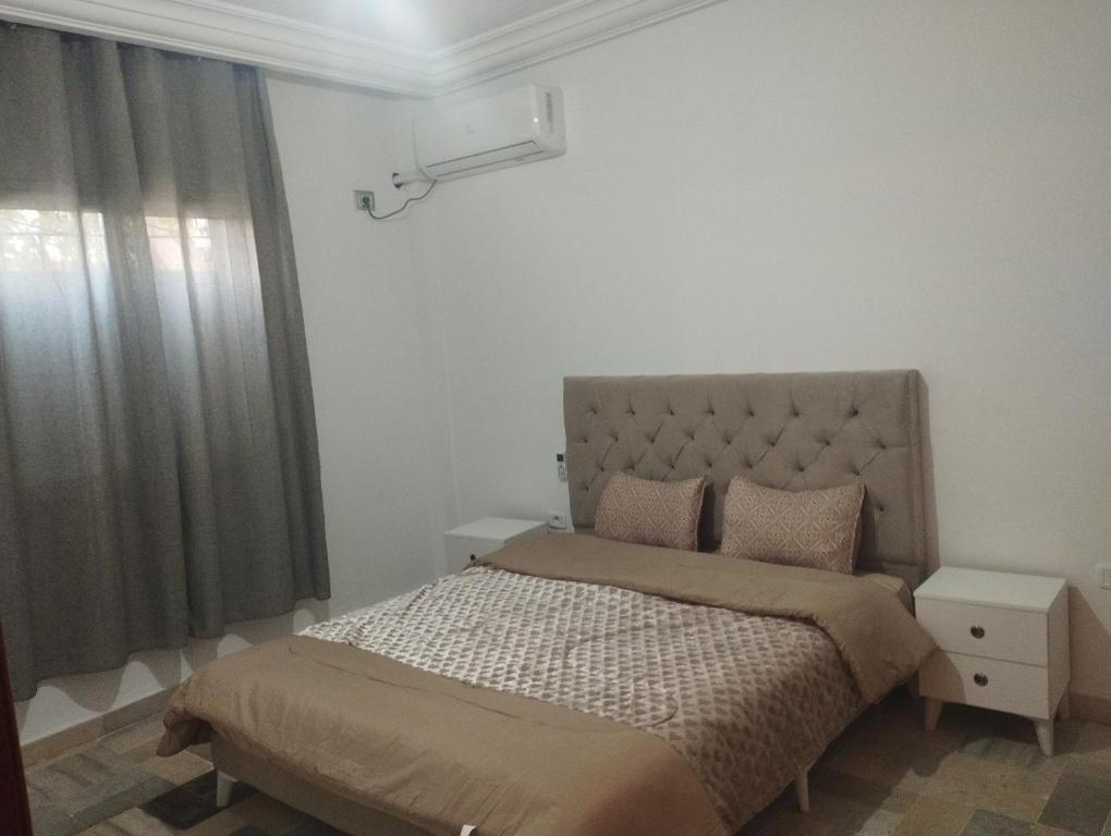 1 dormitorio con 1 cama con cabecero y ventana en Jad tunis, en Túnez