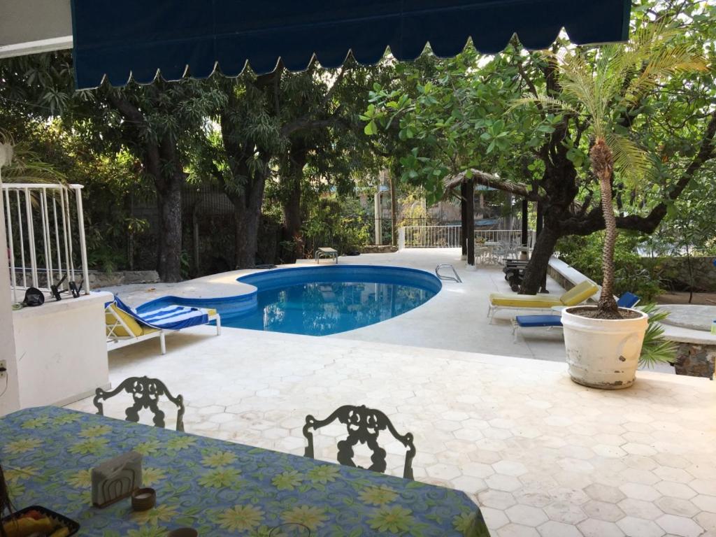 a swimming pool with two chairs and a table and a table sidx sidx at Villa Covadonga in Acapulco