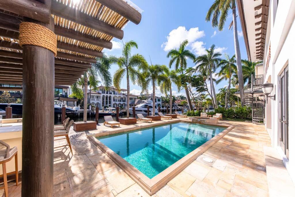 uma piscina com espreguiçadeiras e palmeiras em Tropical Waterfront 7 Bedroom House in Seven Isles em Fort Lauderdale
