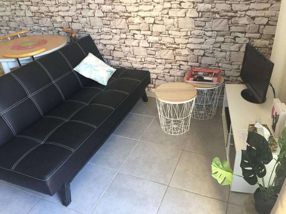 a living room with a black couch and a table at Le Chapitre, au calme de Senlis in Senlis