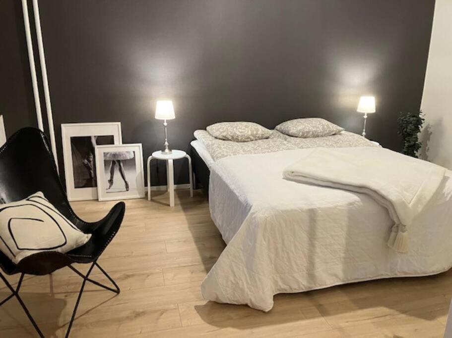 a bedroom with a bed and a chair and two pictures at Kaunis moderni tilava asunto in Rauma