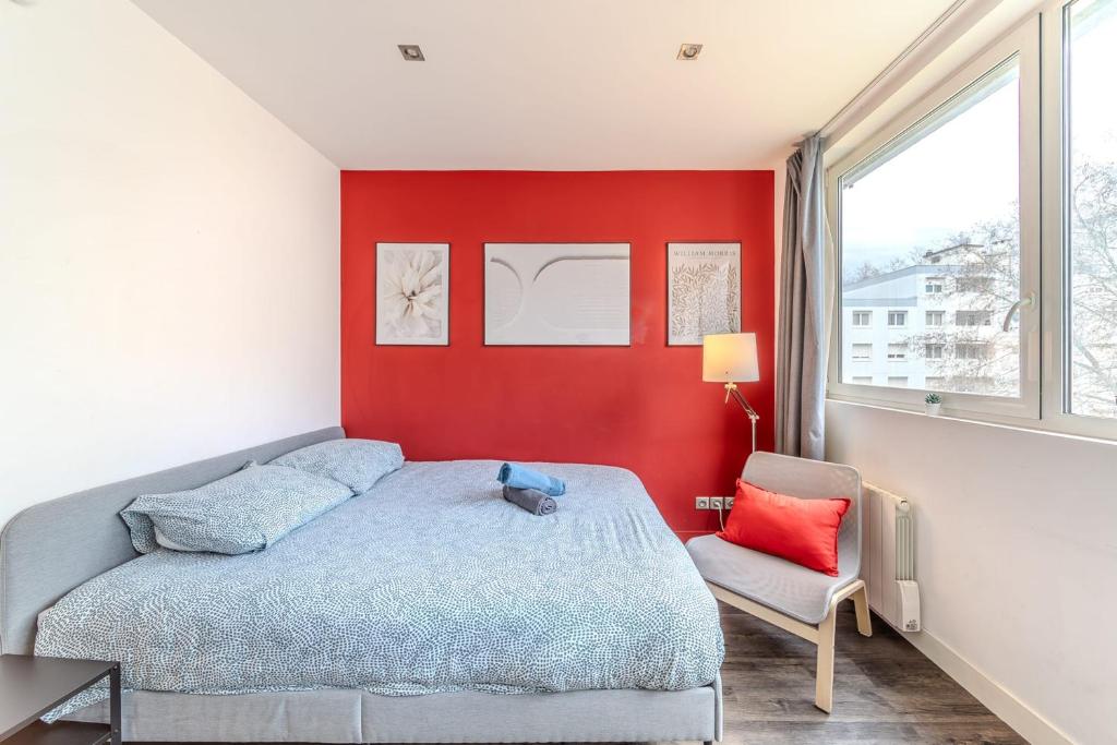 - une chambre avec un lit et un mur rouge dans l'établissement Studio proche tête d'Or 2 personnes Villeurbanne, à Villeurbanne